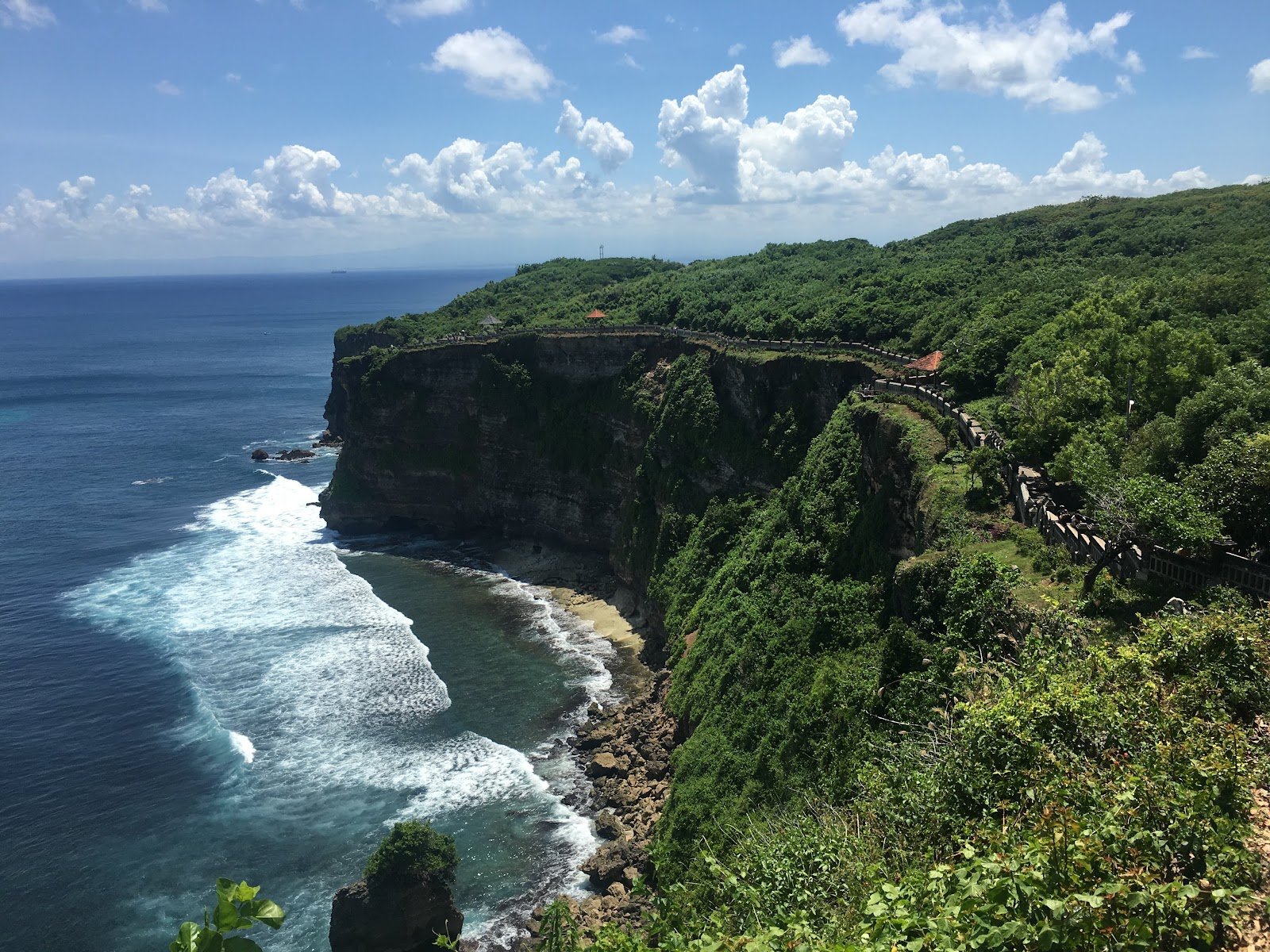 Green-topped cliffs dropping into the sea at Uluwatu, with a walkway along the edge