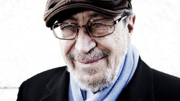Portrait of Edgar Schein in a flat cap, glasses and a blue scarf