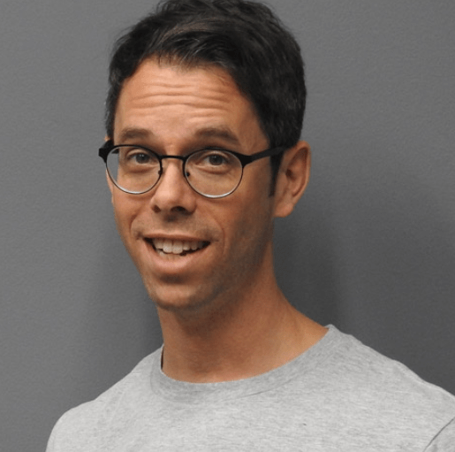 Portrait of a smiling man in round glasses and a grey T-shirt