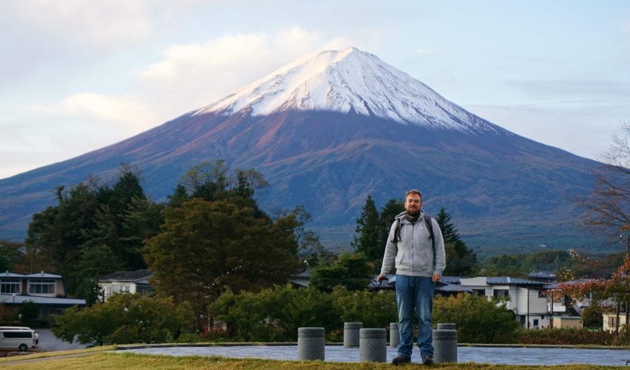 Artur Piszek standing in front of snow-capped Mount Fuji